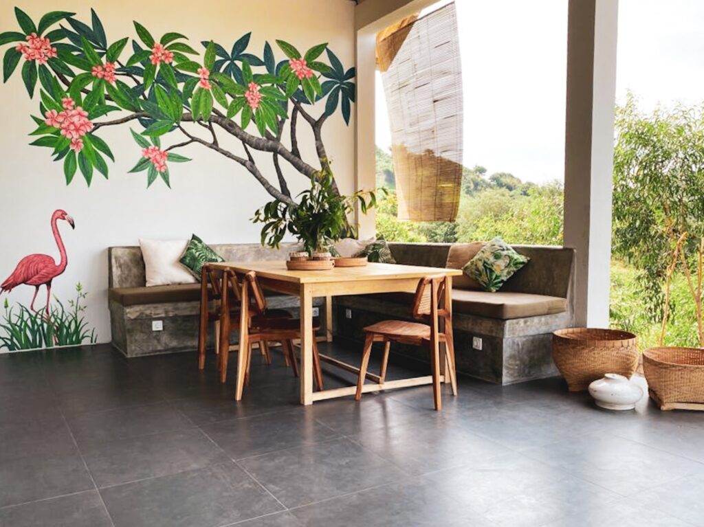 abuLous Place Lombok surf villa dining table area with frangipani and flamingo wall painting